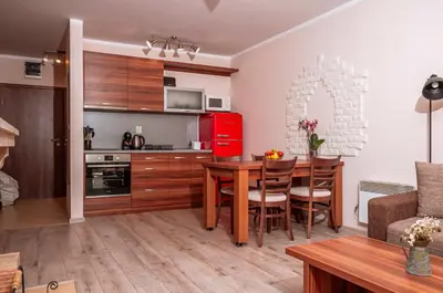 a kitchen and dining room with a table and a red refrigerator at Stand'Art - апартамент , Смолянски езера in Smolyan