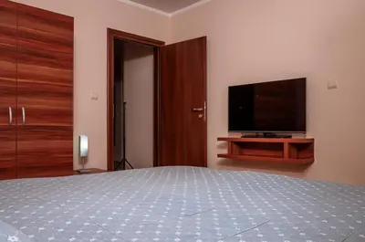 a bedroom with a bed and a flat screen tv at Stand'Art - апартамент , Смолянски езера in Smolyan