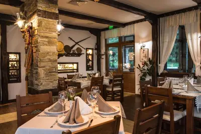a restaurant with tables and chairs and a fireplace at Stand'Art - апартамент , Смолянски езера in Smolyan