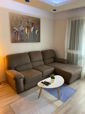 a living room with a brown couch and a table at Modern & Central 1BR Apartment with lovely terrace in Plovdiv