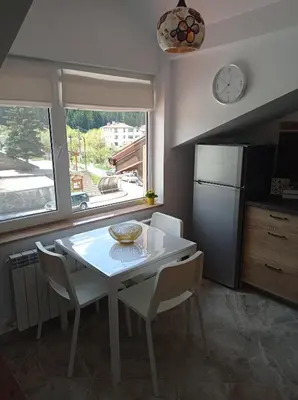a kitchen with a white table and chairs and a clock at Къща за гости-Ганеви in Zmeitsa