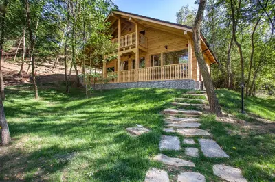 a log cabin in the woods with a path leading to it at Garmen Hills Guest Houses in Garmen