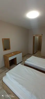 a room with two beds and a desk and a mirror at Хотел-ресторант Русаков in Sandanski