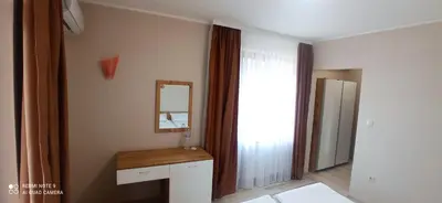 a bedroom with a mirror and a dressing table and a window at Хотел-ресторант Русаков in Sandanski