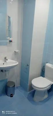 a bathroom with a white toilet and a sink at Хотел-ресторант Русаков in Sandanski