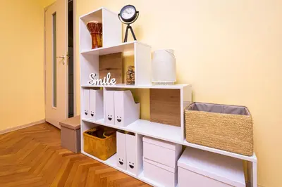 a white shelf with boxes and a clock on a wall at The Cozy Home 1-Bedroom in Central Plovdiv by Flat Mаnager in Plovdiv