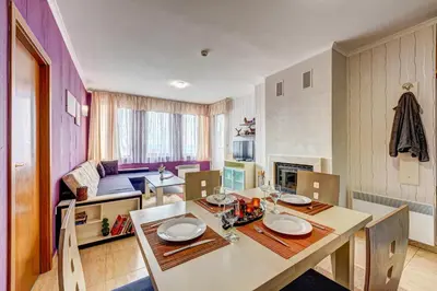 a room with a dining table and a living room at Colorful 2BD Apartment with Indoor Fireplace and Mountain View by Flat Mаnager in Pamporovo