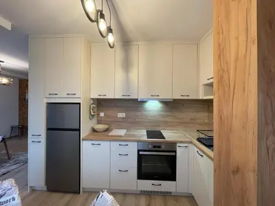 a kitchen with white cabinets and a black refrigerator at Апартамент Стил in Chepelare