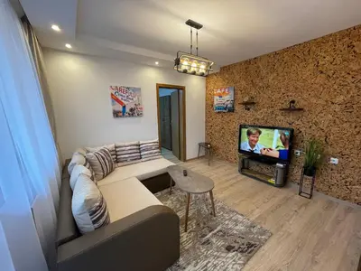 a living room with a couch and a tv at Апартамент Стил in Chepelare