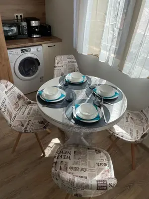 a dining room table with chairs and a washing machine at Апартамент Стил in Chepelare