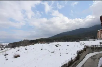 a snow covered field with a fence and mountains at Luxury Suite Ivana in Bansko