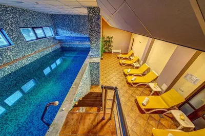 a large swimming pool with yellow chairs in a building at Boho Mountain Studio in Smolyan