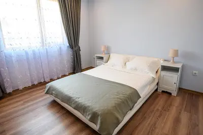 a bedroom with a bed with two night stands and a window at Guest House Dinaya in Dobrinishte