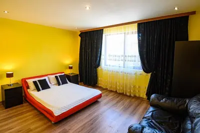 a bedroom with a bed and a yellow wall at Guest House Dinaya in Dobrinishte