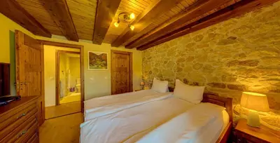 a bedroom with a bed and a stone wall at Къща за гости 