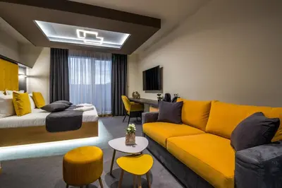 a living room with a yellow couch and a bed at EMAR HOTEL & SPA in Sapareva Banya