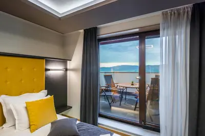 a bedroom with a bed and a balcony with a table at EMAR HOTEL & SPA in Sapareva Banya