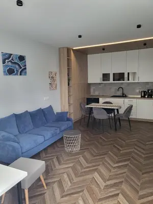 a living room with a blue couch and a table at New luxury apartment next to subway with garage in Sofia