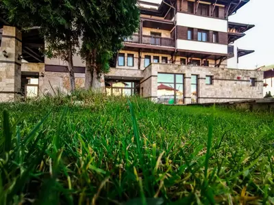 a building in front of a field of grass at Trinity Residence Bansko with Free Shuttle to Gondola in Bansko