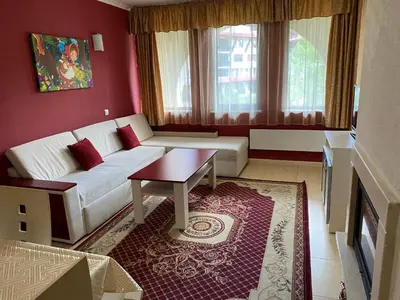 a living room with a white couch and a table at Червената Шапчица Апартамент Гранд Манастира in Pamporovo