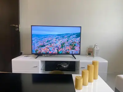 a flat screen tv sitting on top of a white entertainment center at Brand new and modern apartment directly next to the metro station in Sofia