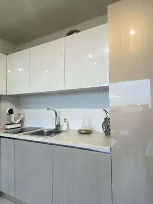 a kitchen with white cabinets and a sink at Brand new and modern apartment directly next to the metro station in Sofia
