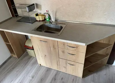 a kitchen counter with a sink and wooden cabinets at Apart Uzunov-3 in Hisarya