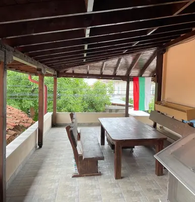 a wooden table and a bench on a patio at Apart Uzunov-3 in Hisarya