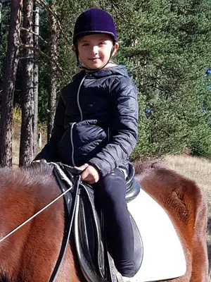 a young child riding on the back of a horse at Dona Guest House - Horse Riding in Koprivshtitsa
