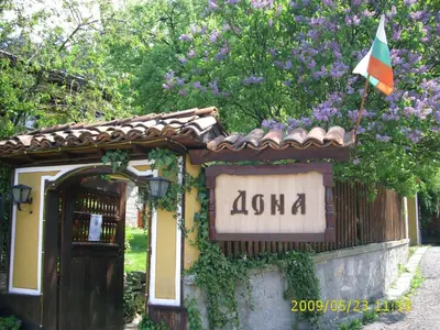 a sign in front of a building with a flag at Dona Guest House - Horse Riding in Koprivshtitsa