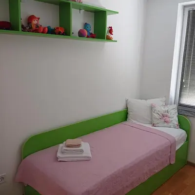 a bedroom with a bed with a pink and green headboard at Апартамент за гости Дарива in Smolyan