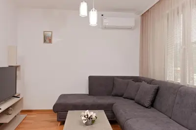 a living room with a gray couch and a table at Апартамент за гости Дарива in Smolyan