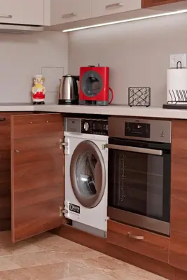 a kitchen with a washing machine and a microwave at Апартамент за гости Дарива in Smolyan