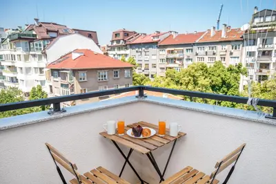 a table with a plate of food on a balcony at Modern and Spacious apartments in the City Centre in Sofia