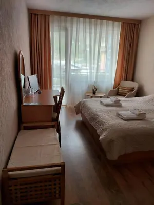 a hotel room with two beds and a desk at Хотел Лагуна in Dospat
