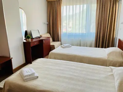 a hotel room with two beds and a desk and a window at Хотел Лагуна in Dospat
