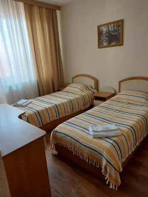 two beds in a hotel room with a window at Хотел Лагуна in Dospat