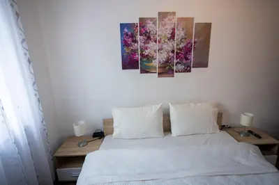 a bedroom with a bed with two paintings on the wall at Karastoyanovi's apartment 2 in Sofia