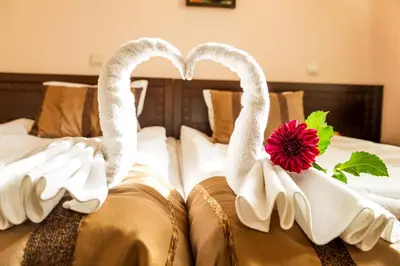 two swansuitsrendered to look like they are on a bed at Family Hotel Teteven in Teteven