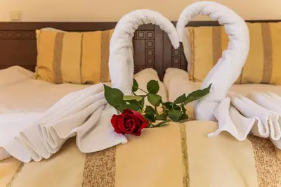 a bed with white towels and a rose on it at Family Hotel Teteven in Teteven