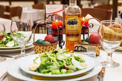a table with a plate of salad and a bottle of wine at Family Hotel Teteven in Teteven