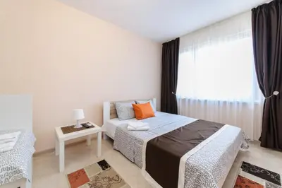 a bedroom with a bed and a table and a window at Sandanski Peak Guest Rooms in Sandanski