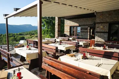 a restaurant with tables and chairs with mountains in the background at Hotel Leshten in Leshten