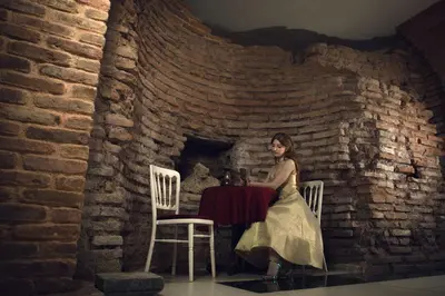 a woman sitting at a table in front of a brick wall at Villa Flavia Heritage Boutique Hotel in Plovdiv