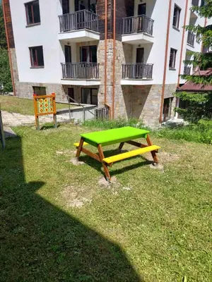 a green picnic table in front of a building at KLEPALSKI - Mountain Studio in Borovets
