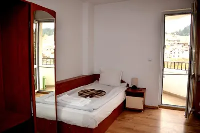 a small bedroom with a bed and a large window at Family Hotel Daisy in Borino