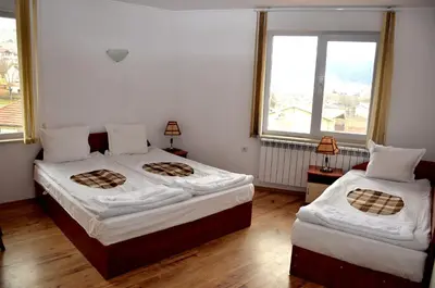 two beds in a room with two windows at Family Hotel Daisy in Borino