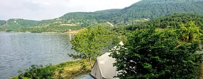 a tent next to a lake with trees and mountains at Lakeview Glamping in Staro Myasto