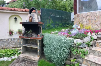 a garden with a stone wall and a bird feeder at Sunny House in Madzhare