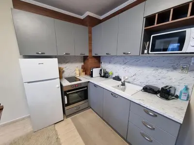 a kitchen with white cabinets and a white refrigerator at Гранд Манастира Лукс in Pamporovo